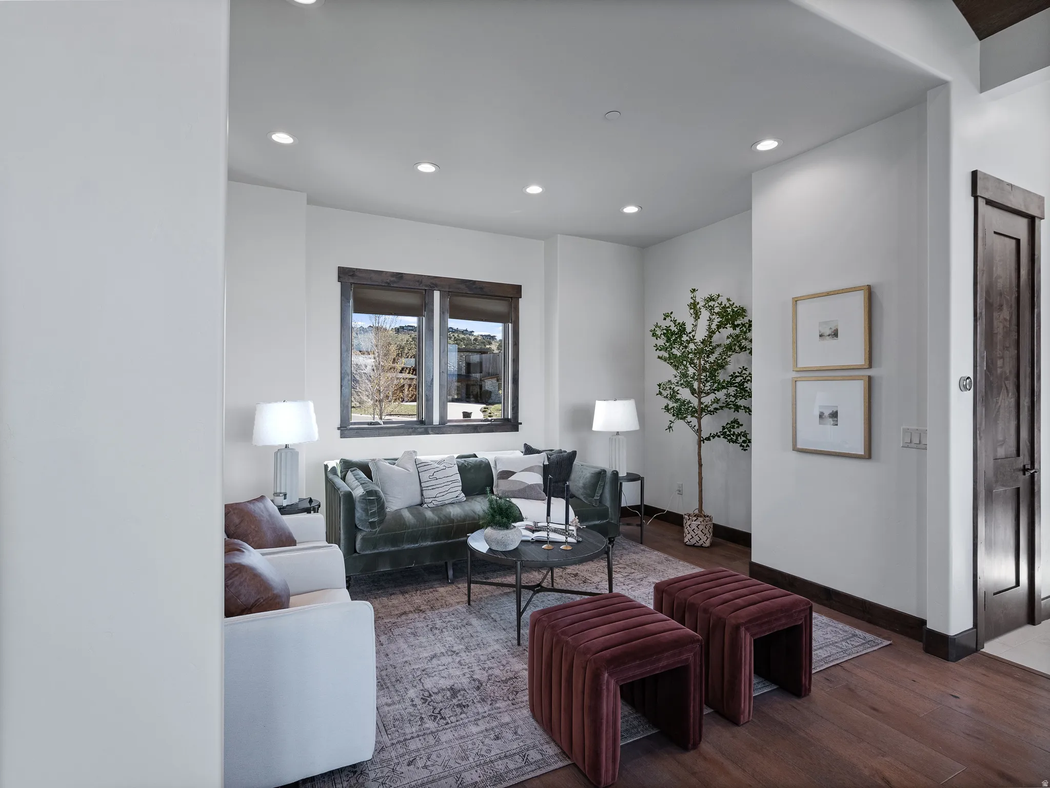 Living area featuring recessed lighting, a wooden door with dark trim, dark wood-finish flooring, and multi-pane windows with dark wood trim
