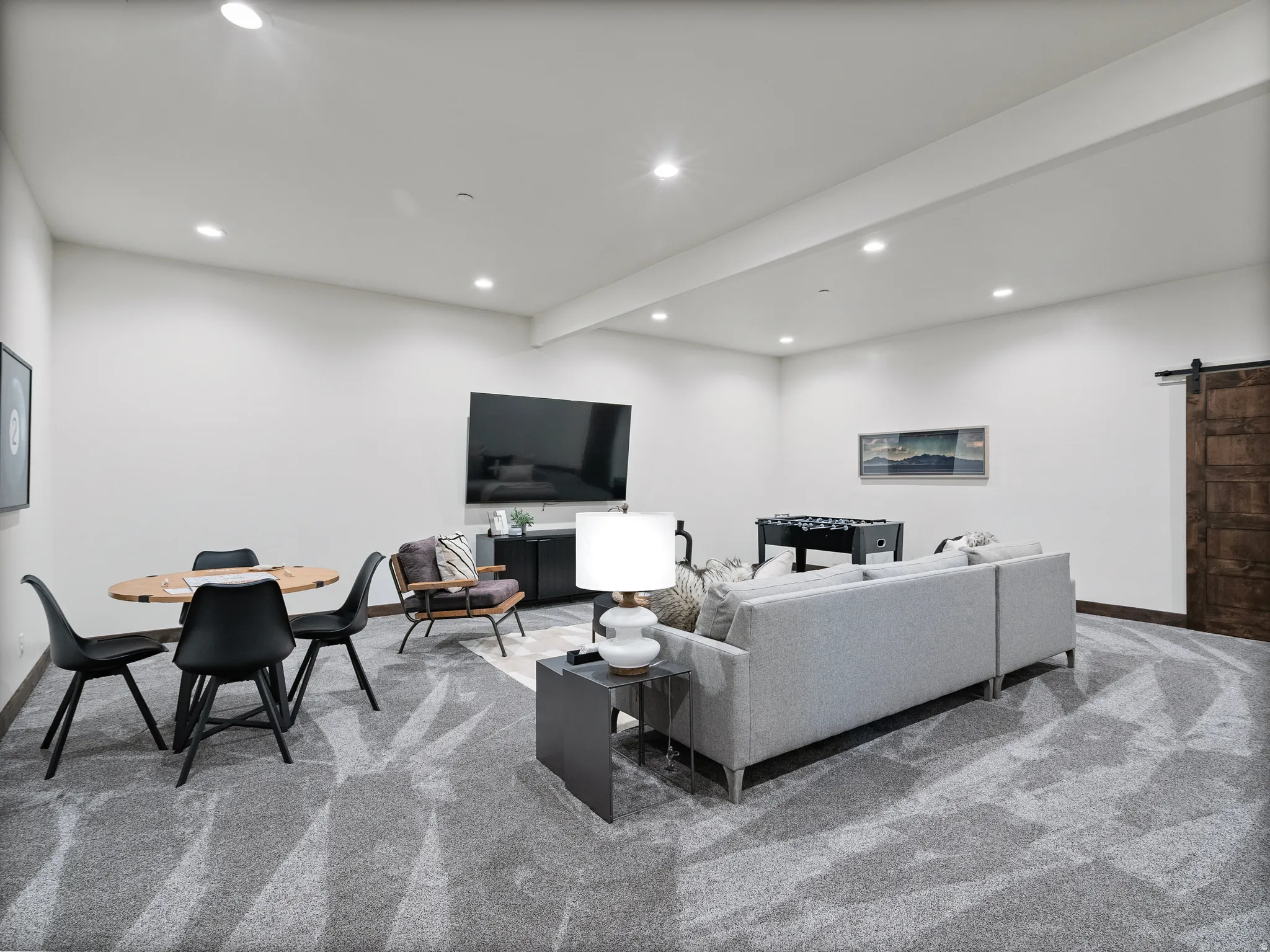 Living room featuring a barn door, light colored carpet, beam ceiling, and recessed lighting