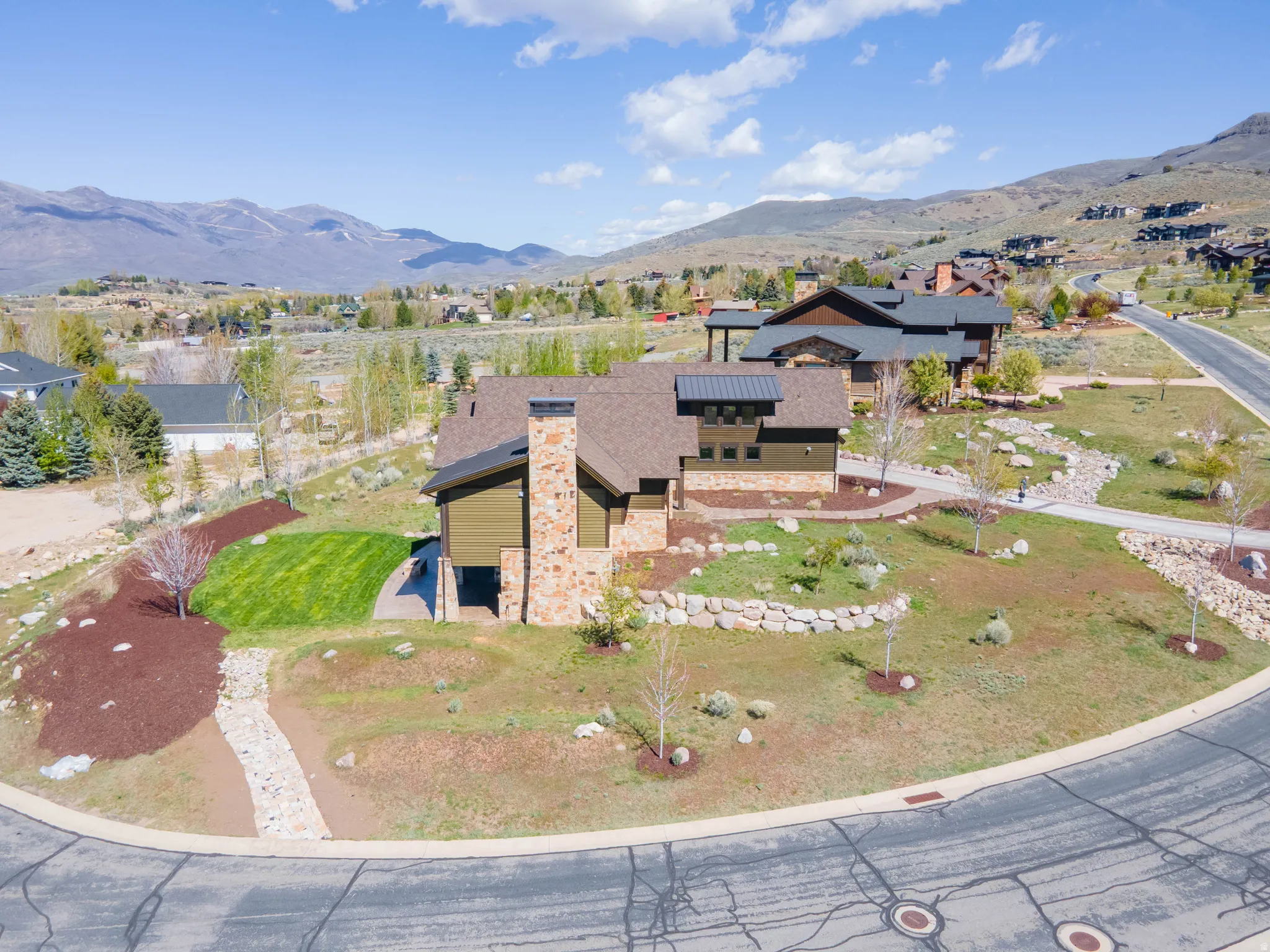 View of front of property with solar panels, a mountain view, stone siding, a front lawn, and a chimney