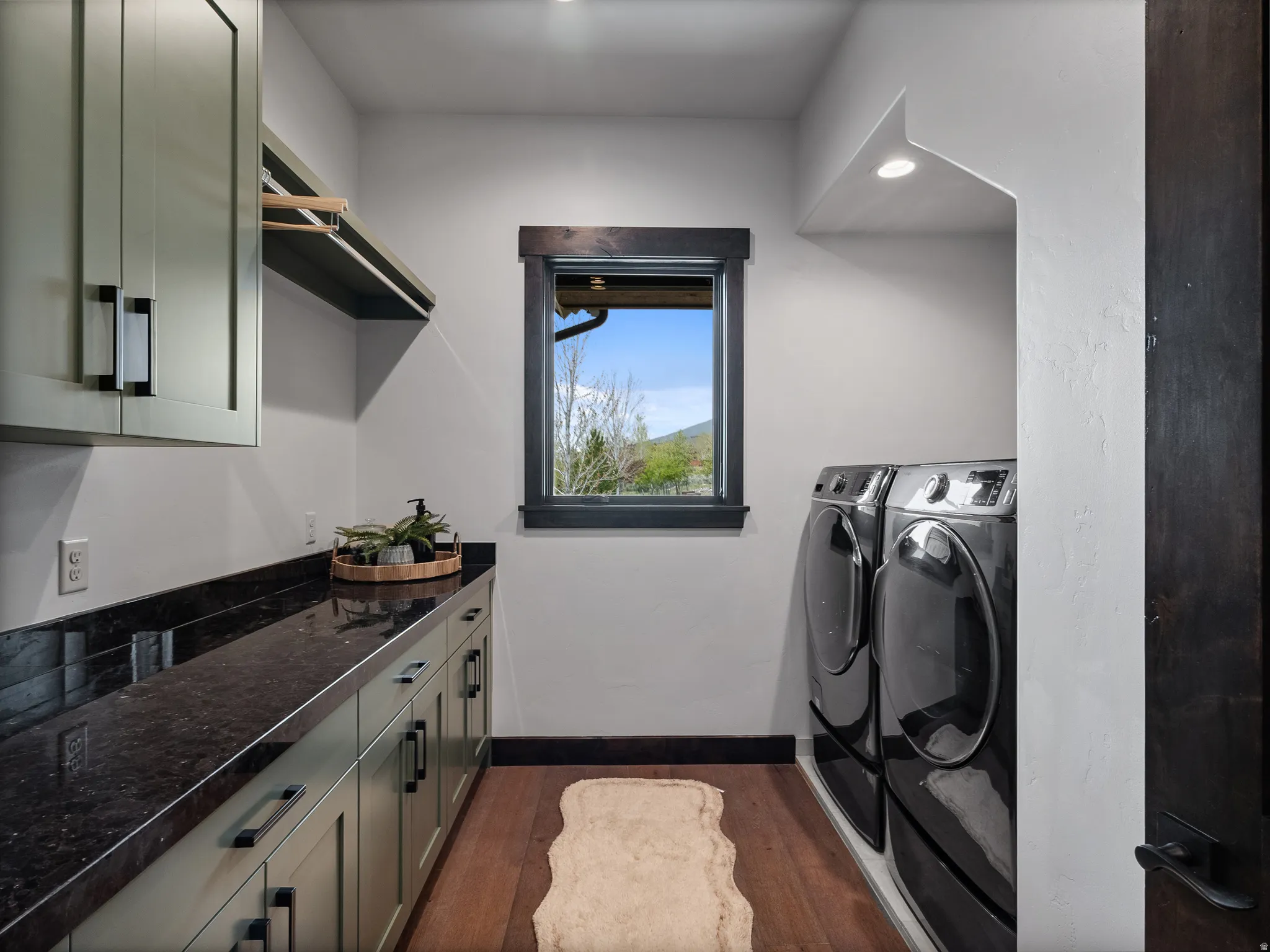 Laundry area with dark wood-style flooring, washer and clothes dryer, cabinet space, and recessed lighting
