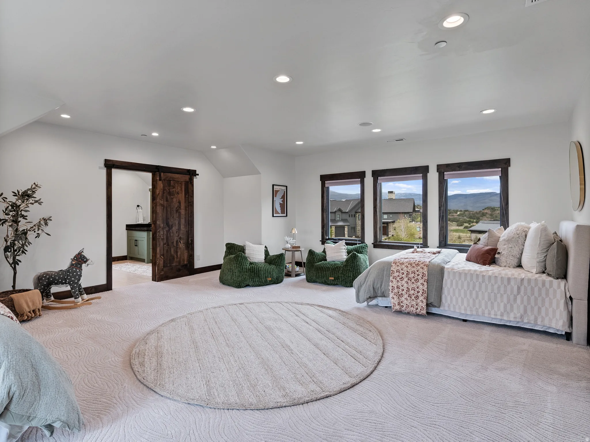 Bedroom with a barn door, light colored carpet, recessed lighting, and ensuite bathroom