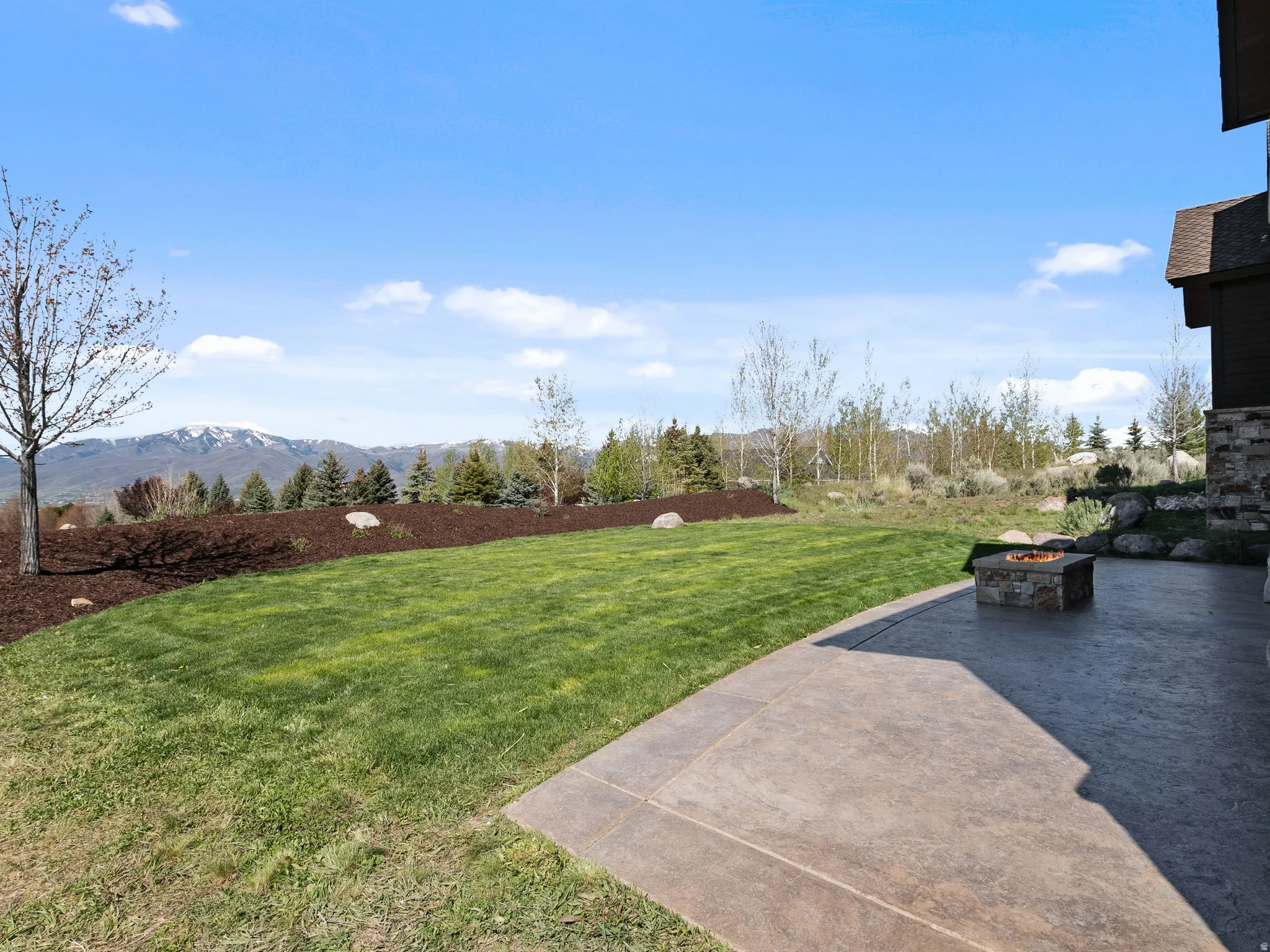 View of green lawn with an outdoor fire pit and a mountain view