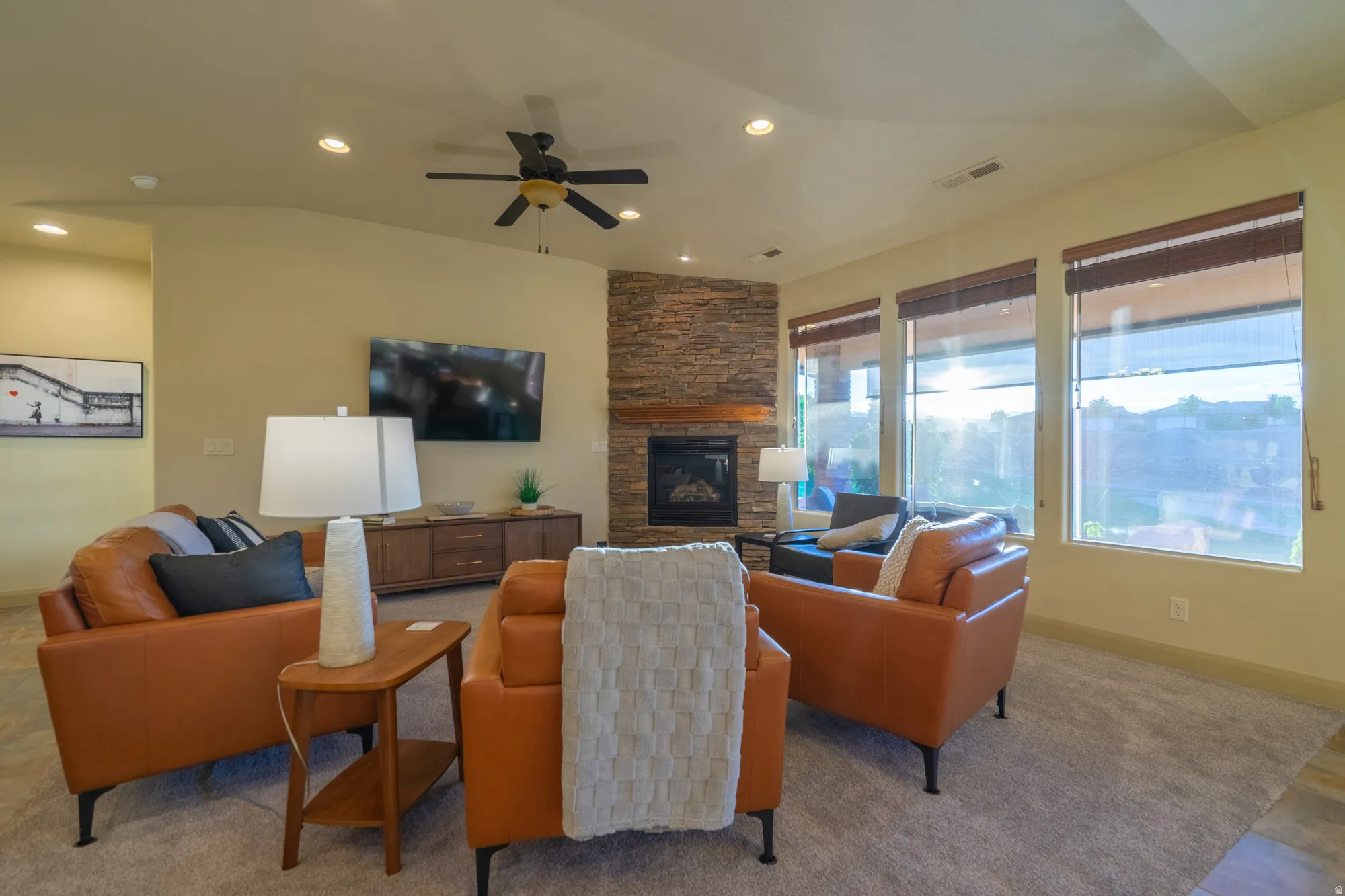 Living room with a ceiling fan, a fireplace, lofted ceiling, and recessed lighting
