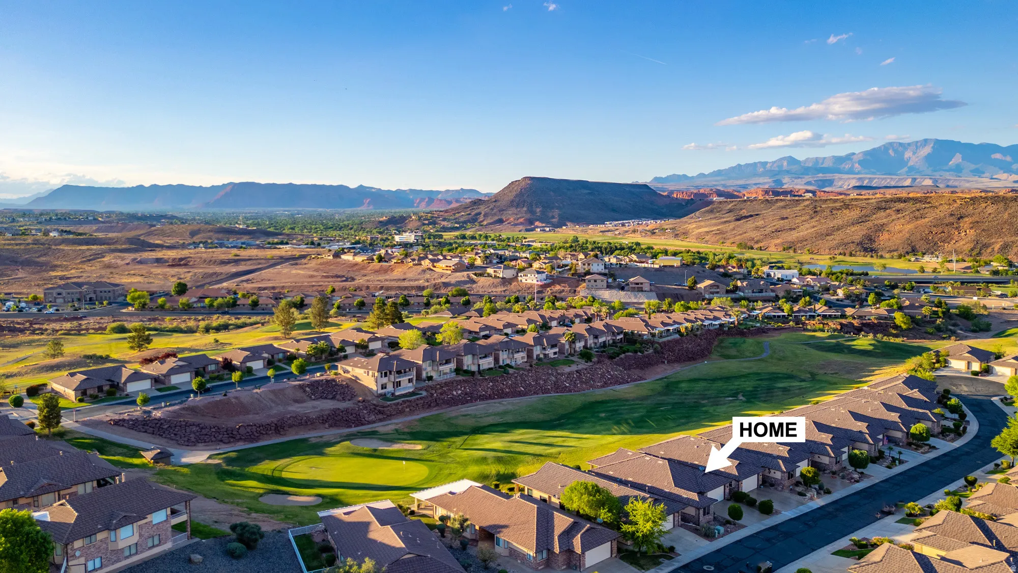 Aerial view of residential area with a mountain backdrop and a local golf course