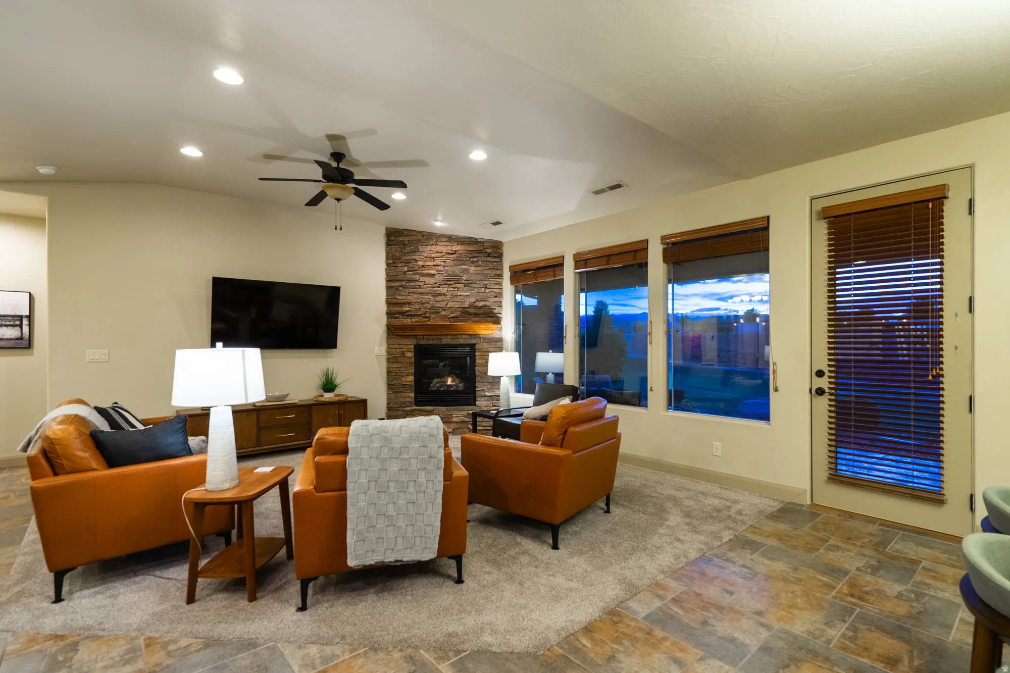 Living area featuring stone finish flooring, ceiling fan, a fireplace, recessed lighting, and vaulted ceiling