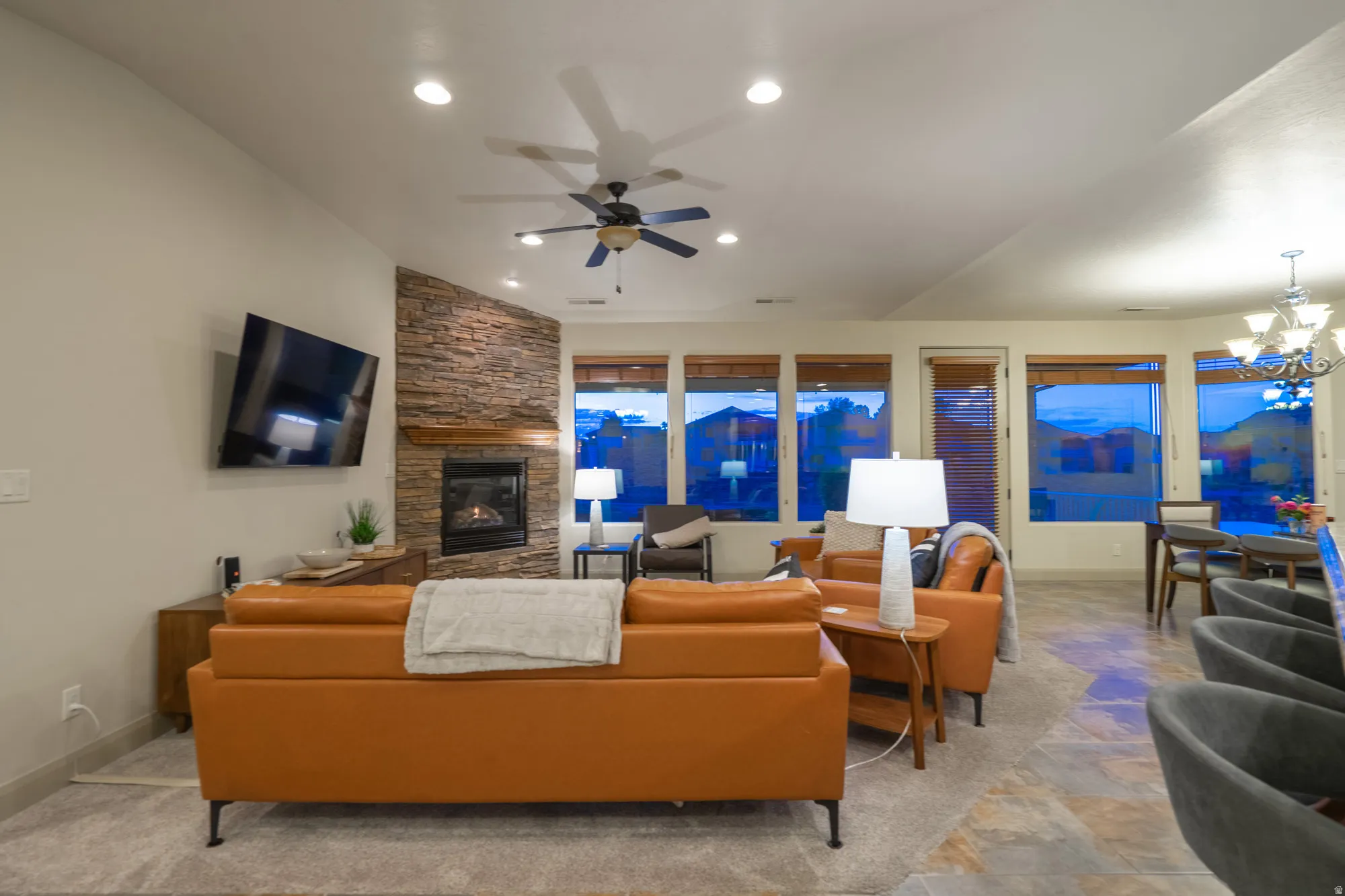 Living area with a fireplace, stone finish flooring, a ceiling fan, and a chandelier