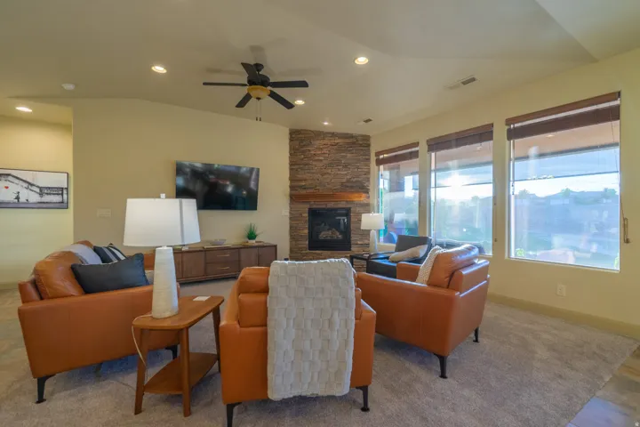 Living room with a ceiling fan, a fireplace, lofted ceiling, and recessed lighting