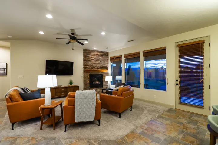 Living area featuring stone finish flooring, ceiling fan, a fireplace, recessed lighting, and vaulted ceiling