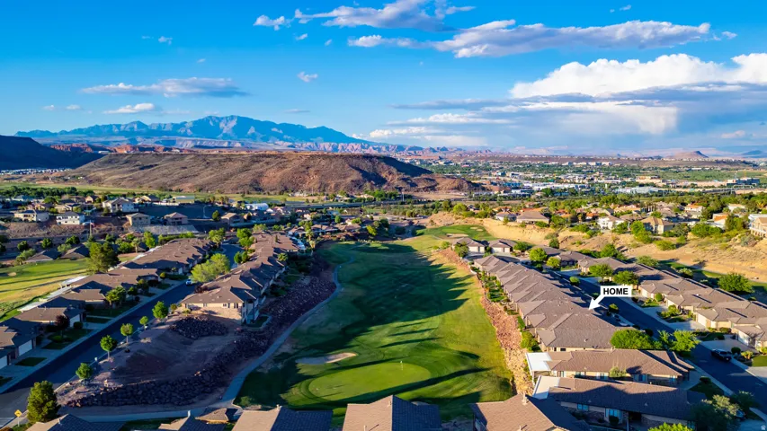 Aerial view of residential area featuring a mountain backdrop and a golf club