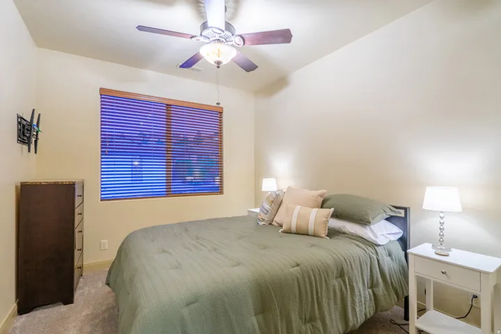 Carpeted bedroom featuring a ceiling fan and baseboards