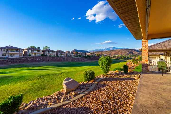 View of green lawn featuring a patio area, view of golf course, a mountain view, and a residential view