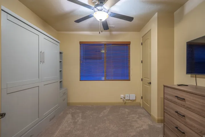 Unfurnished bedroom featuring dark carpet and a ceiling fan