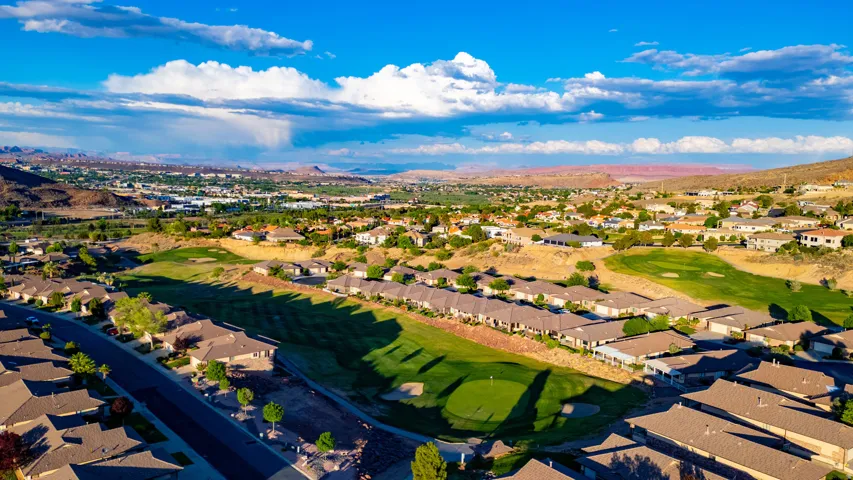Aerial perspective of suburban area featuring a mountain backdrop and a golf club