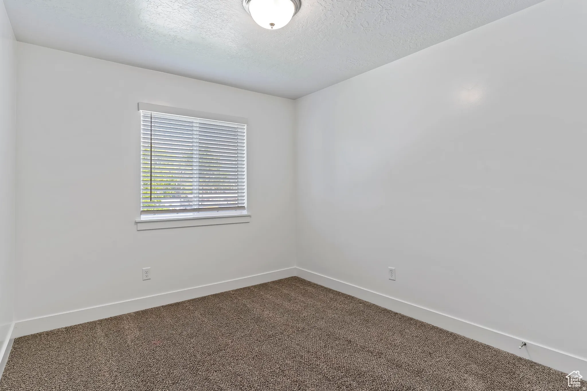 Empty room with dark carpet and a textured ceiling