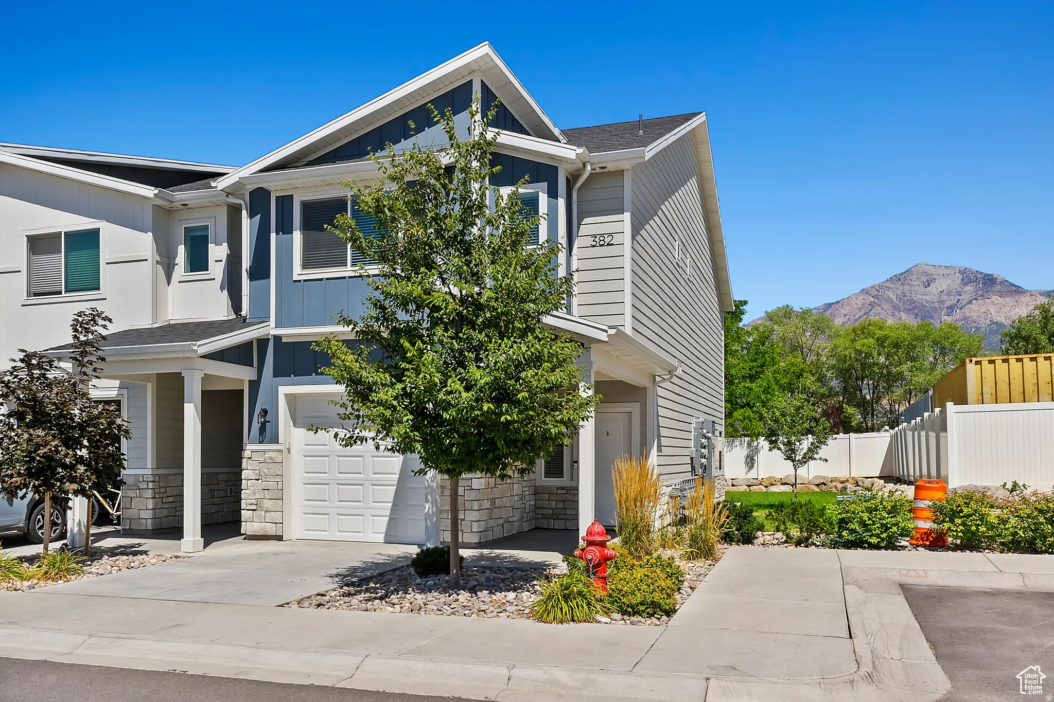 View of front of home with stone siding, an attached garage, a mountain view, and driveway