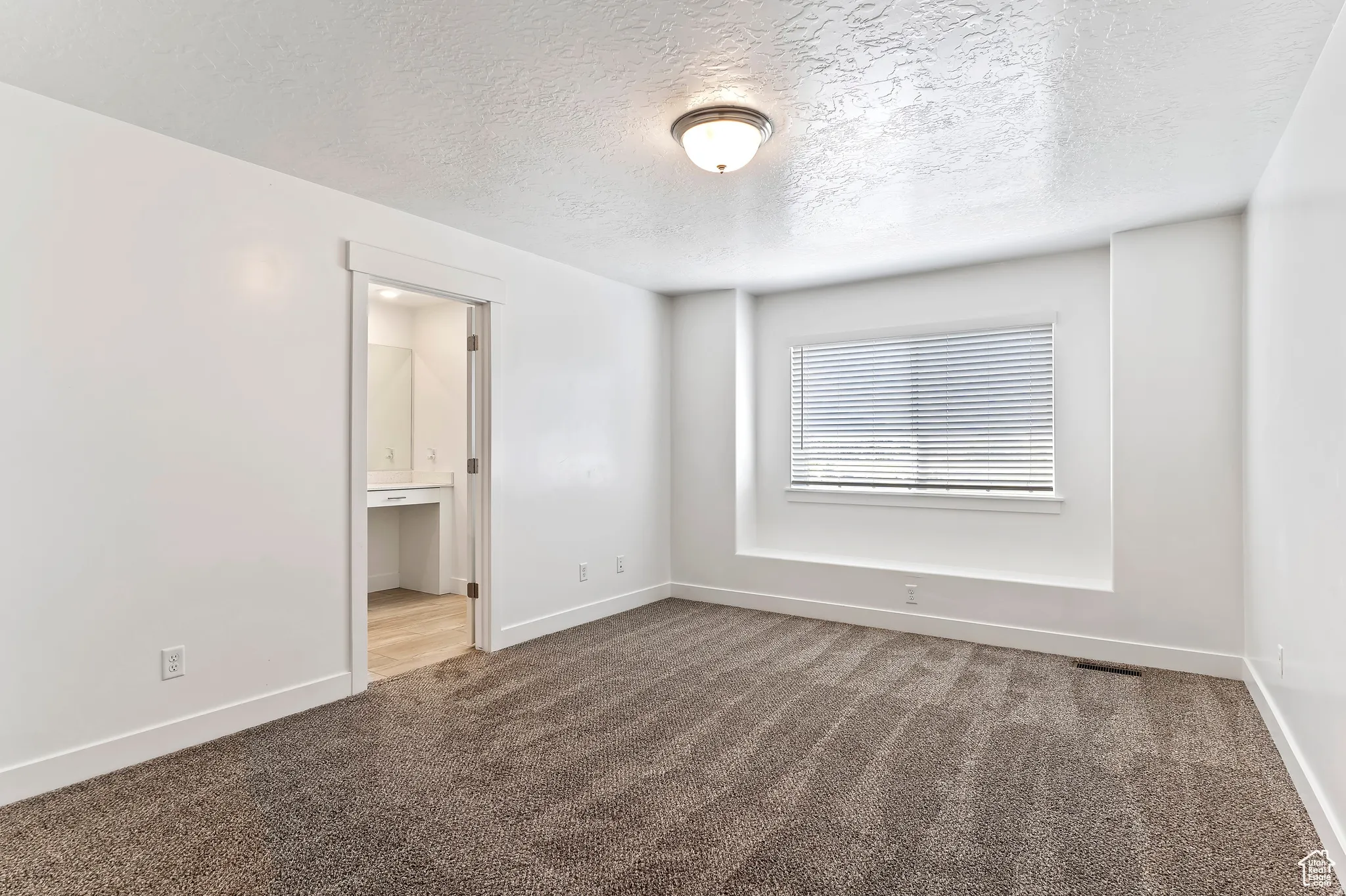 Empty room featuring a textured ceiling and carpet