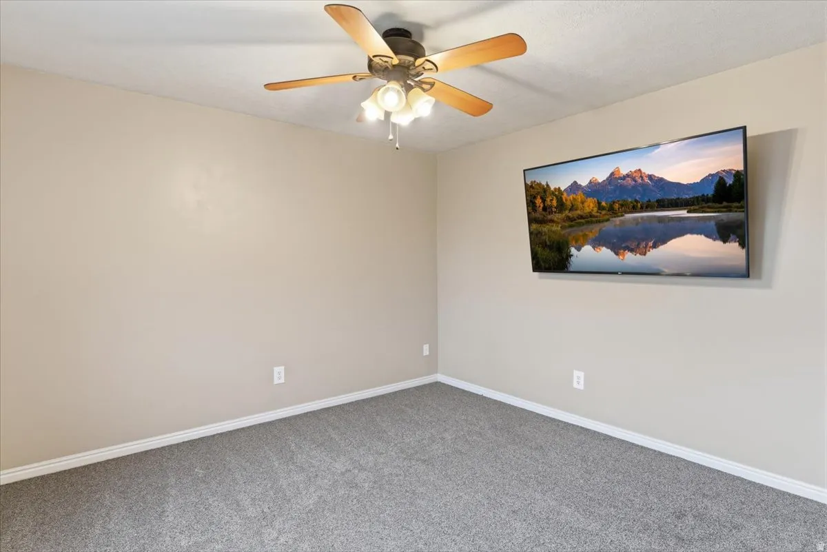 Carpeted empty room with baseboards and a ceiling fan