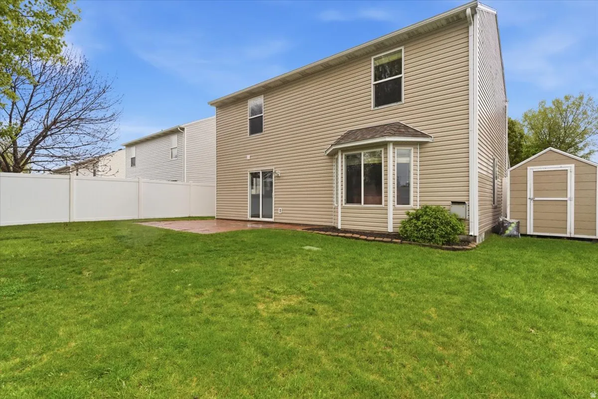 Back of property featuring a storage shed and a patio