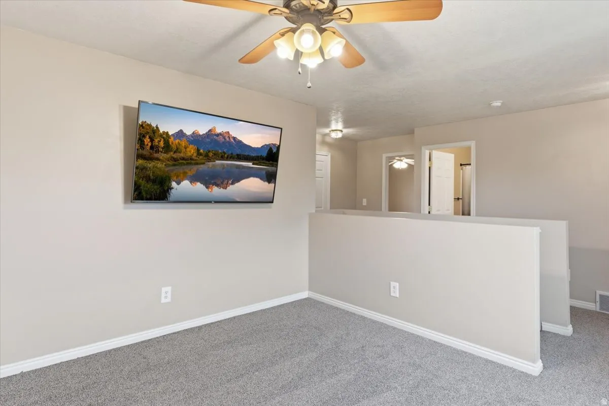 Carpeted spare room featuring a ceiling fan
