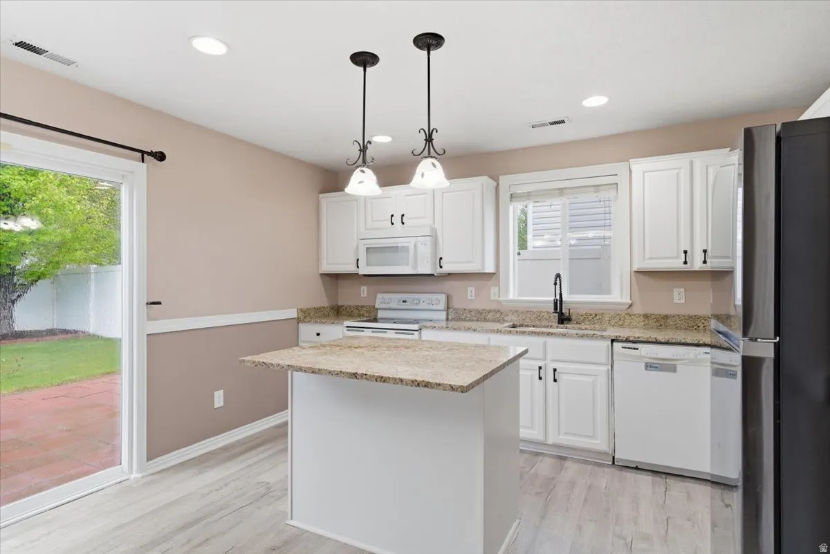 Kitchen with white cabinetry, light wood finished floors, and white appliances