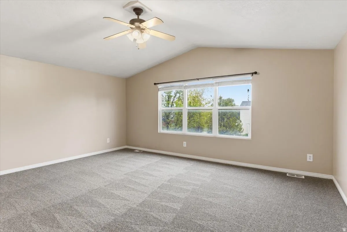Unfurnished room with ceiling fan and light colored carpet