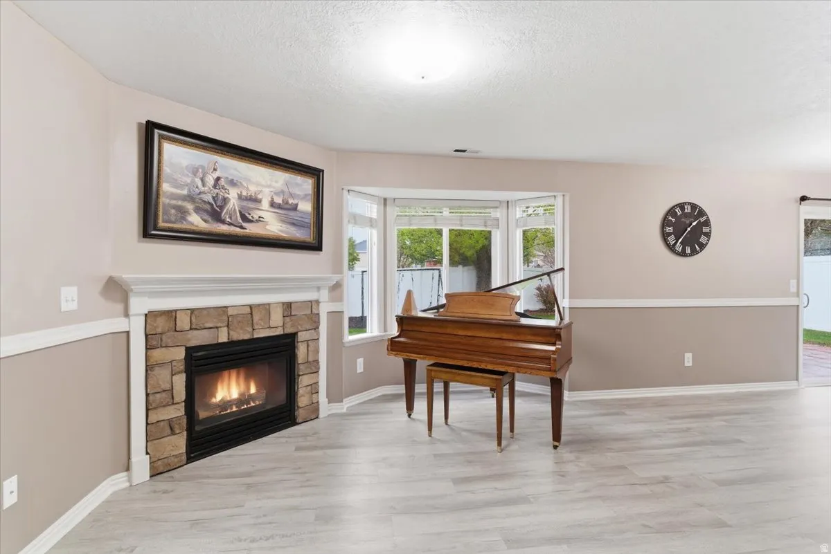 Living area featuring a fireplace, light wood-style floors, and a textured ceiling