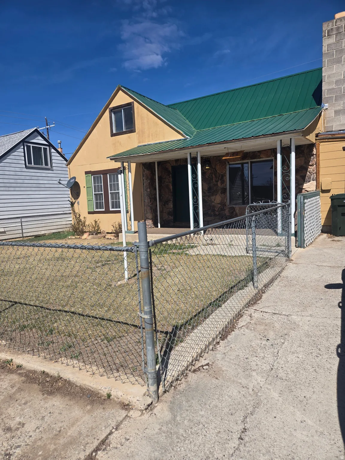 View of front of property with a metal roof, a gate, covered porch, and a fenced front yard