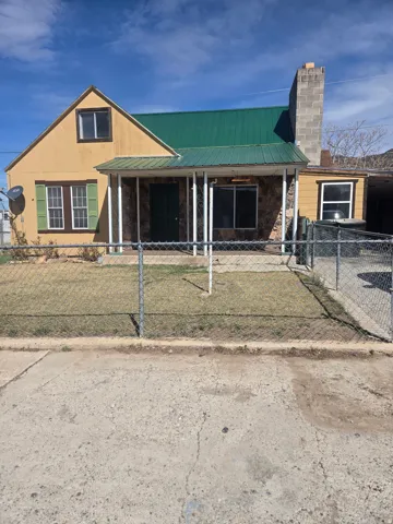 View of front of home featuring a chimney, a metal roof, and a fenced front yard