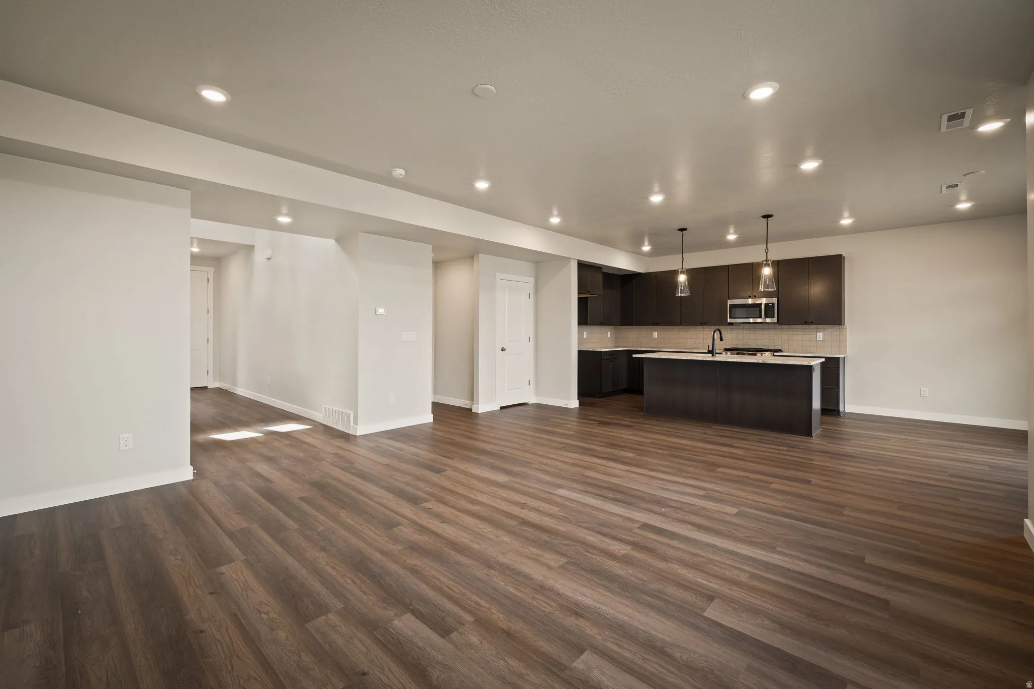 Unfurnished living room with recessed lighting and dark wood-style flooring