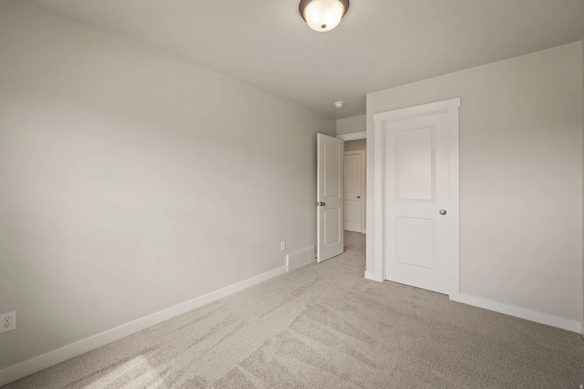 Spare room featuring baseboards and light colored carpet