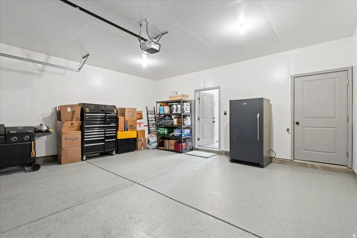 Garage featuring freestanding refrigerator and a garage door opener