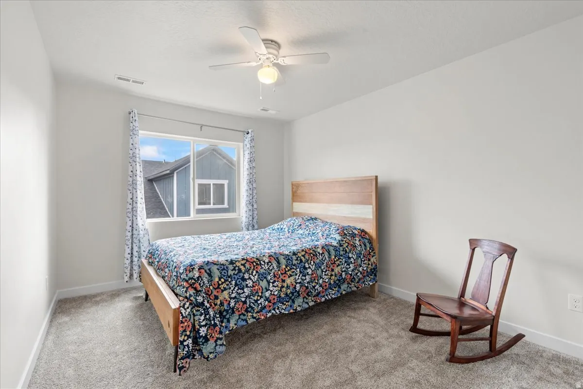 Bedroom with a ceiling fan, light carpet, and a textured ceiling