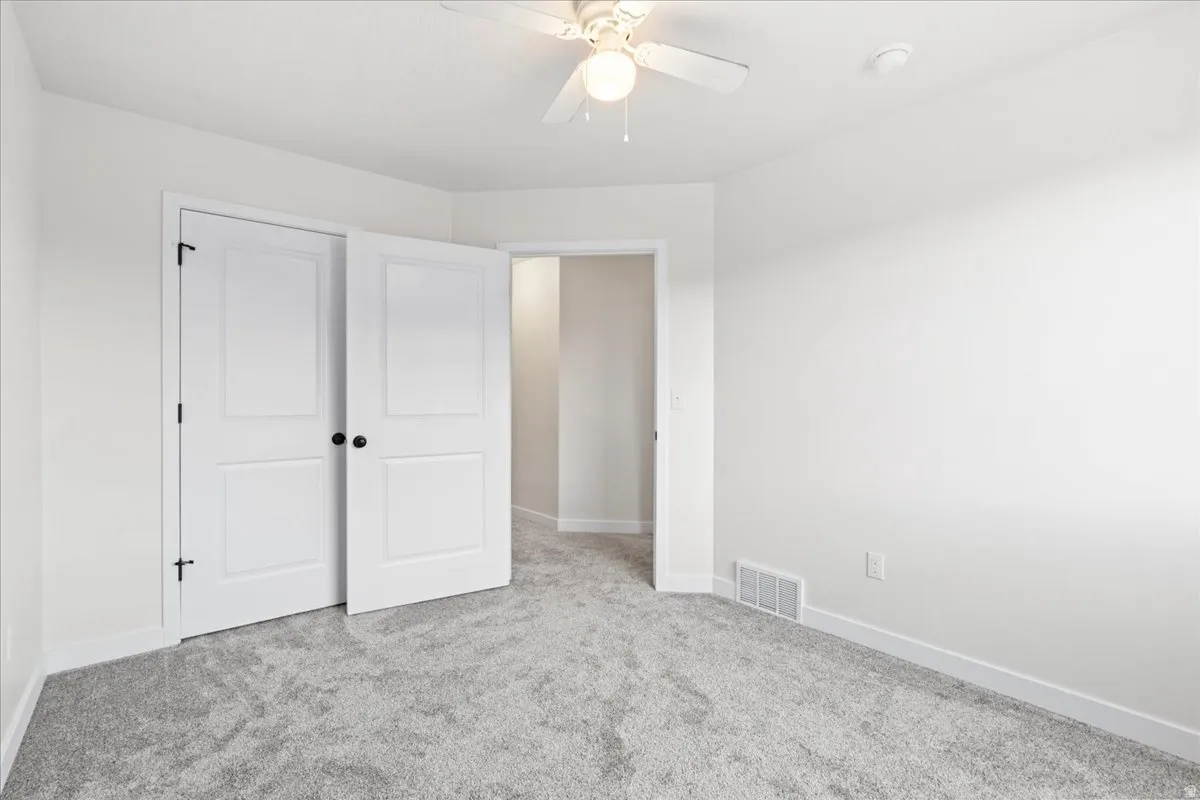 Unfurnished bedroom featuring light carpet and ceiling fan