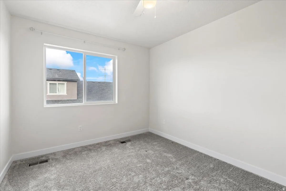 Spare room featuring light colored carpet and a ceiling fan