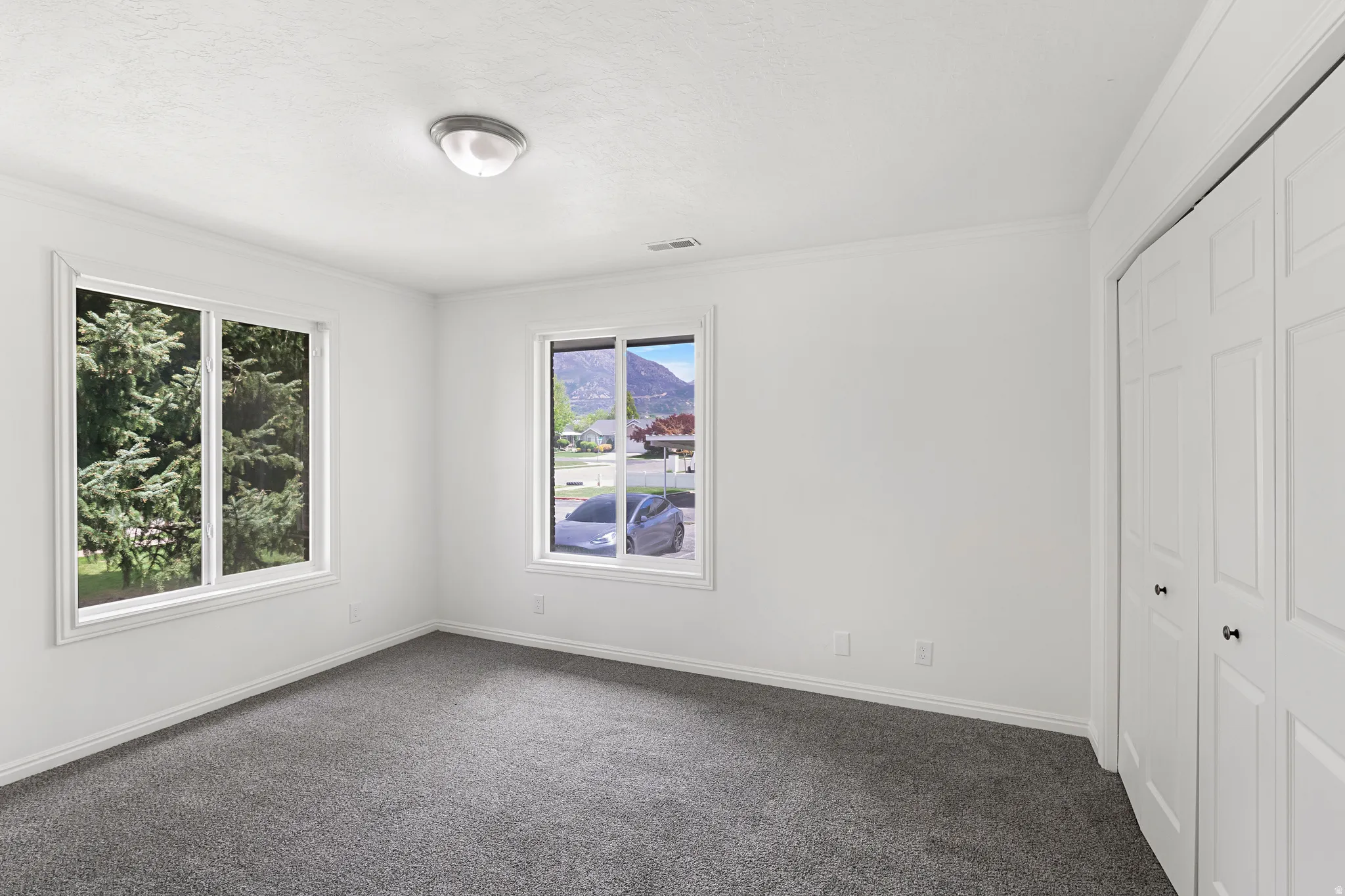 Unfurnished bedroom with a closet, dark carpet, and crown molding