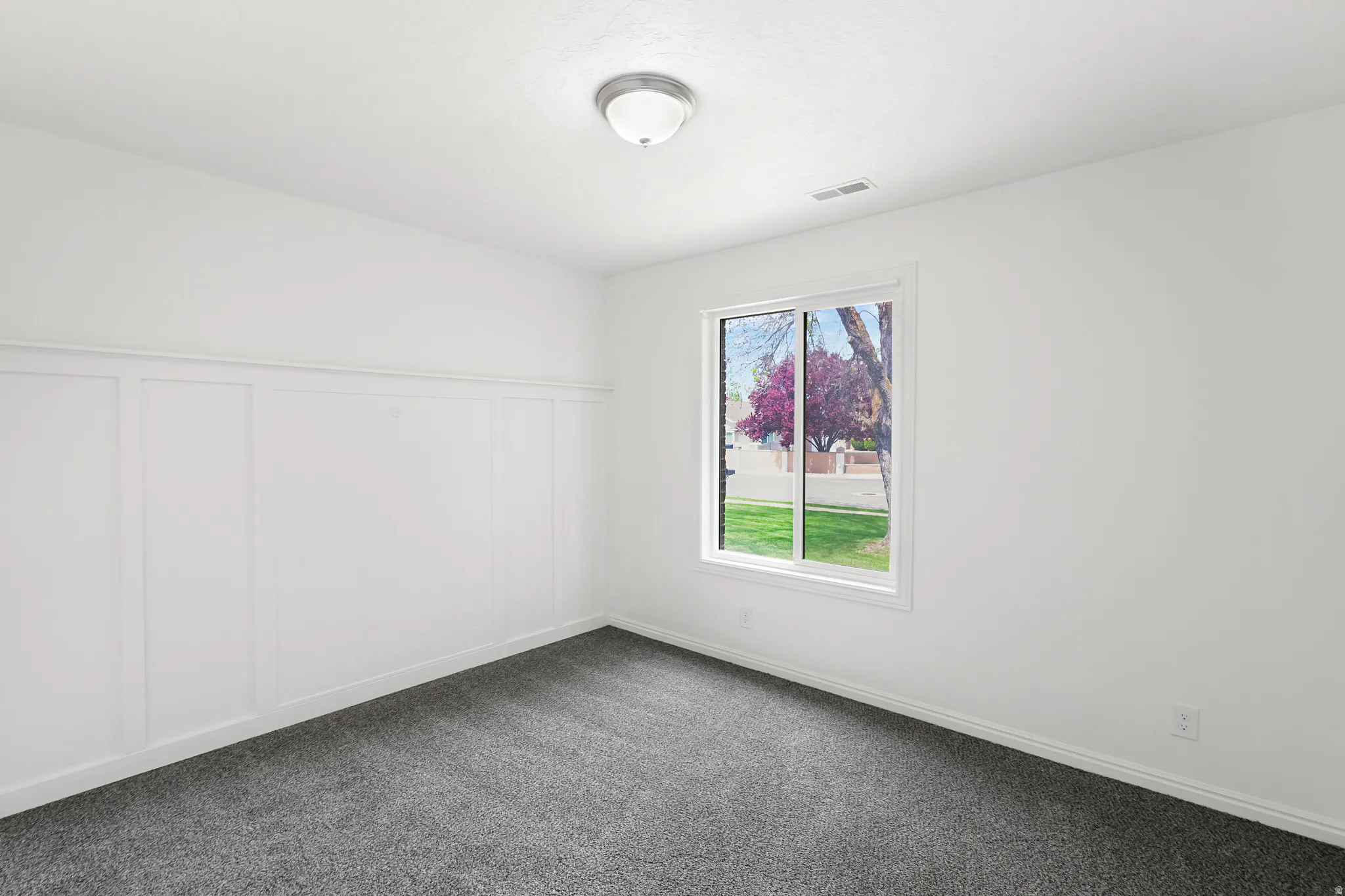 Empty room with a decorative wall, a wainscoted wall, and dark carpet