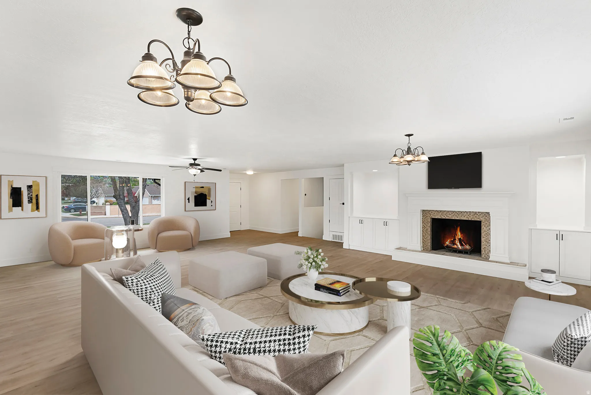 Living area with a chandelier, ceiling fan, light wood-style flooring, and a warm lit fireplace