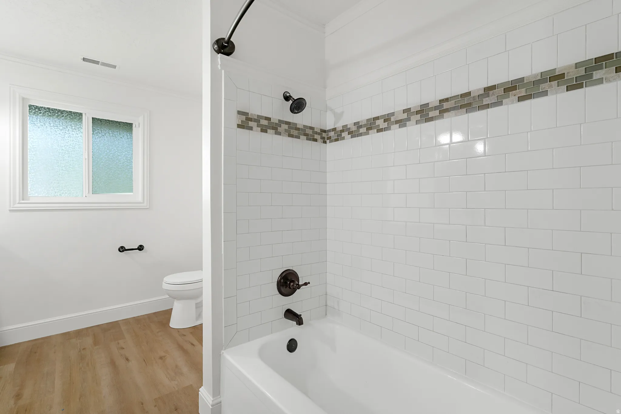 Full bathroom with crown molding, light wood-type flooring, and shower / bathtub combination