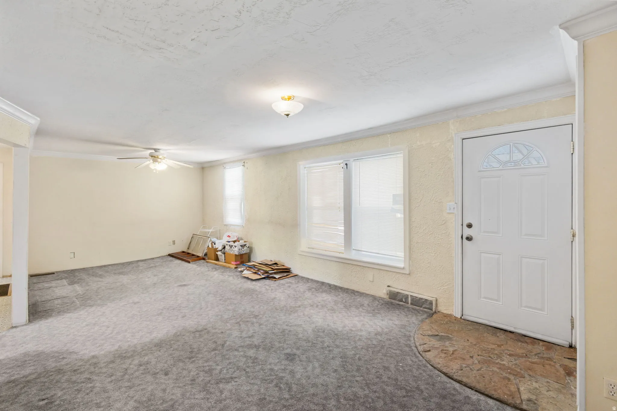Foyer entrance with carpet flooring, ornamental molding, and ceiling fan