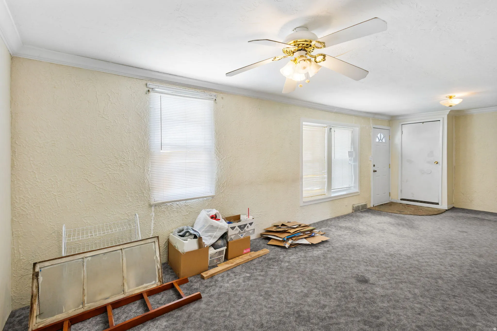 Spare room with a textured wall, carpet flooring, a ceiling fan, ornamental molding, and plenty of natural light
