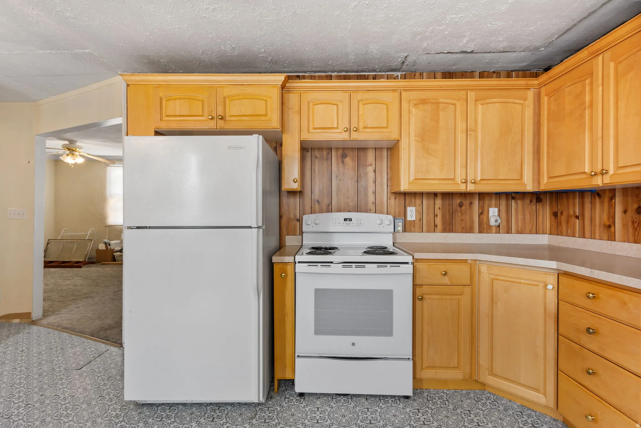 Kitchen with white appliances, light wood finish cabinets, light countertops, and ceiling fan