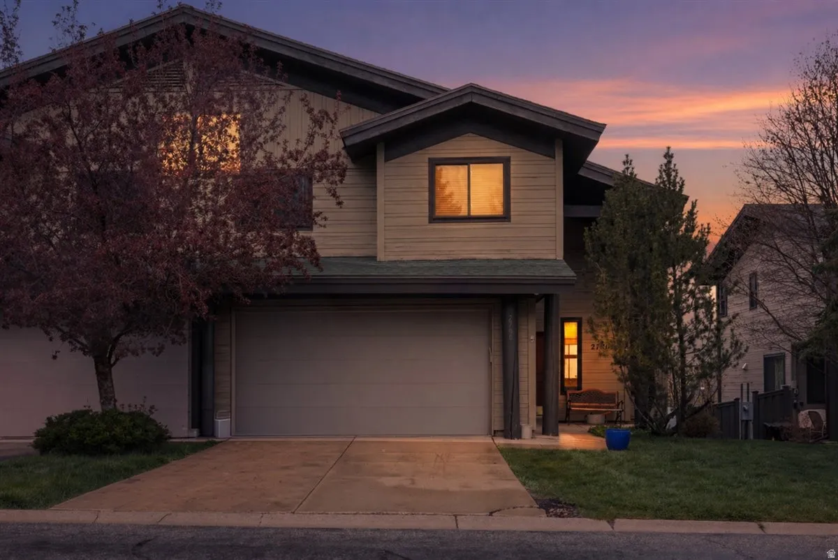 View of front of property featuring a garage, concrete driveway, and a lawn