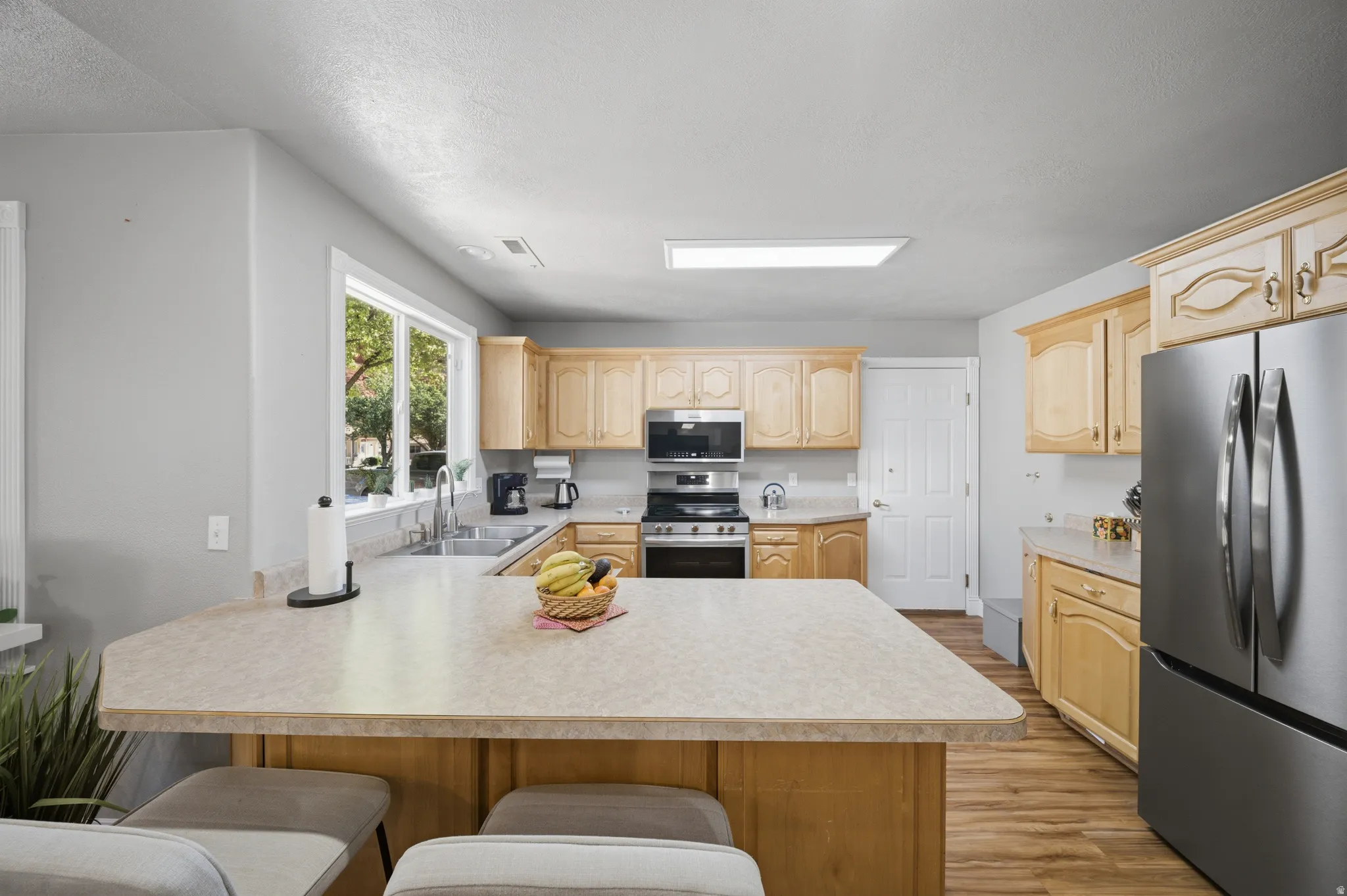 Kitchen featuring a peninsula, a breakfast bar area, stainless steel appliances, light countertops, and a textured ceiling