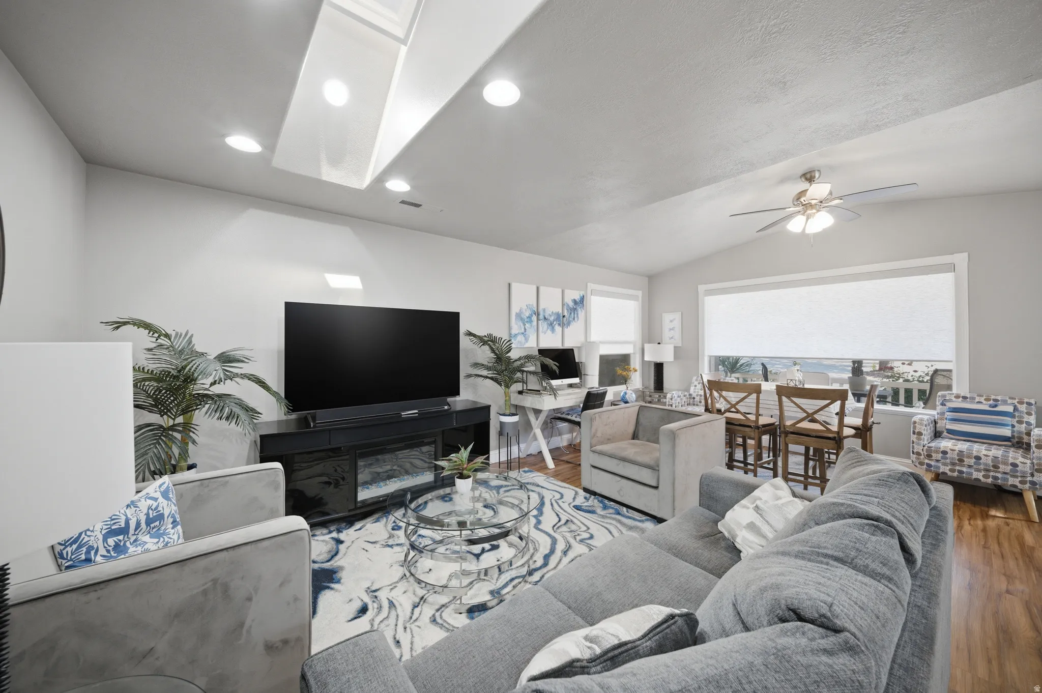 Living room featuring ceiling fan, wood finished floors, vaulted ceiling, and recessed lighting