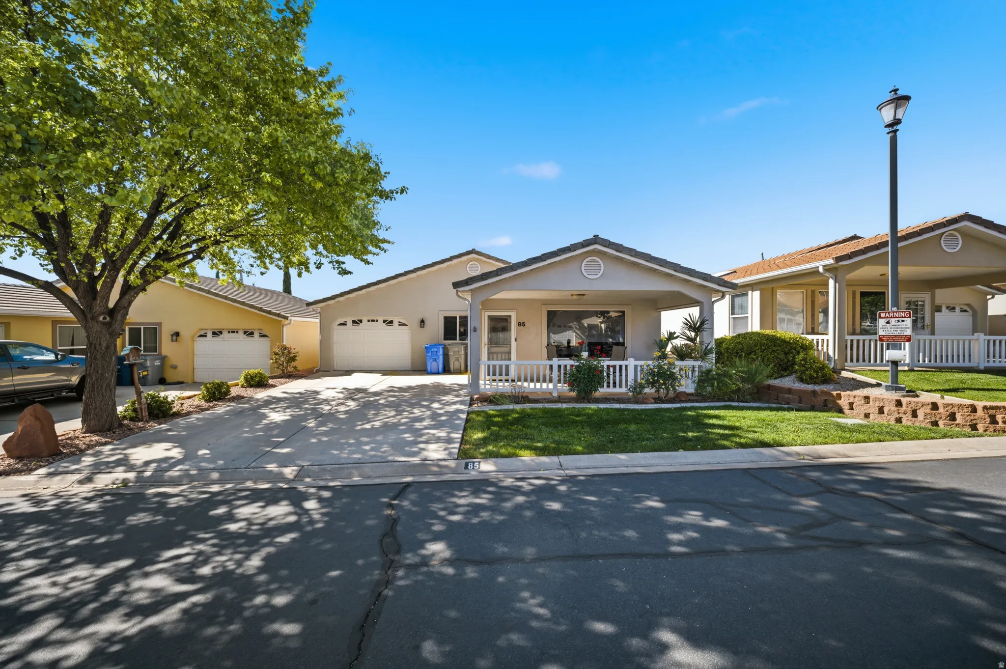 Ranch-style home with an attached garage, a front lawn, concrete driveway, stucco siding, and covered porch