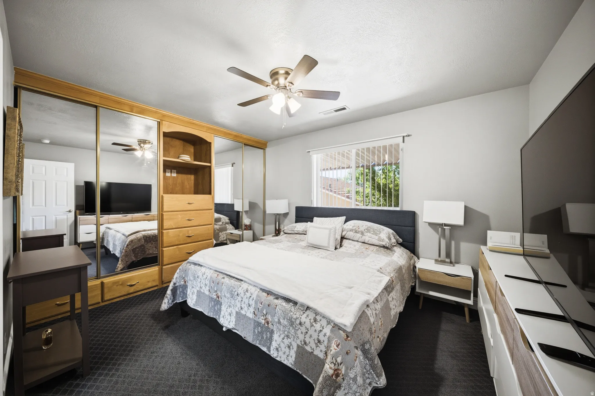 Bedroom with two closets, a ceiling fan, and dark colored carpet