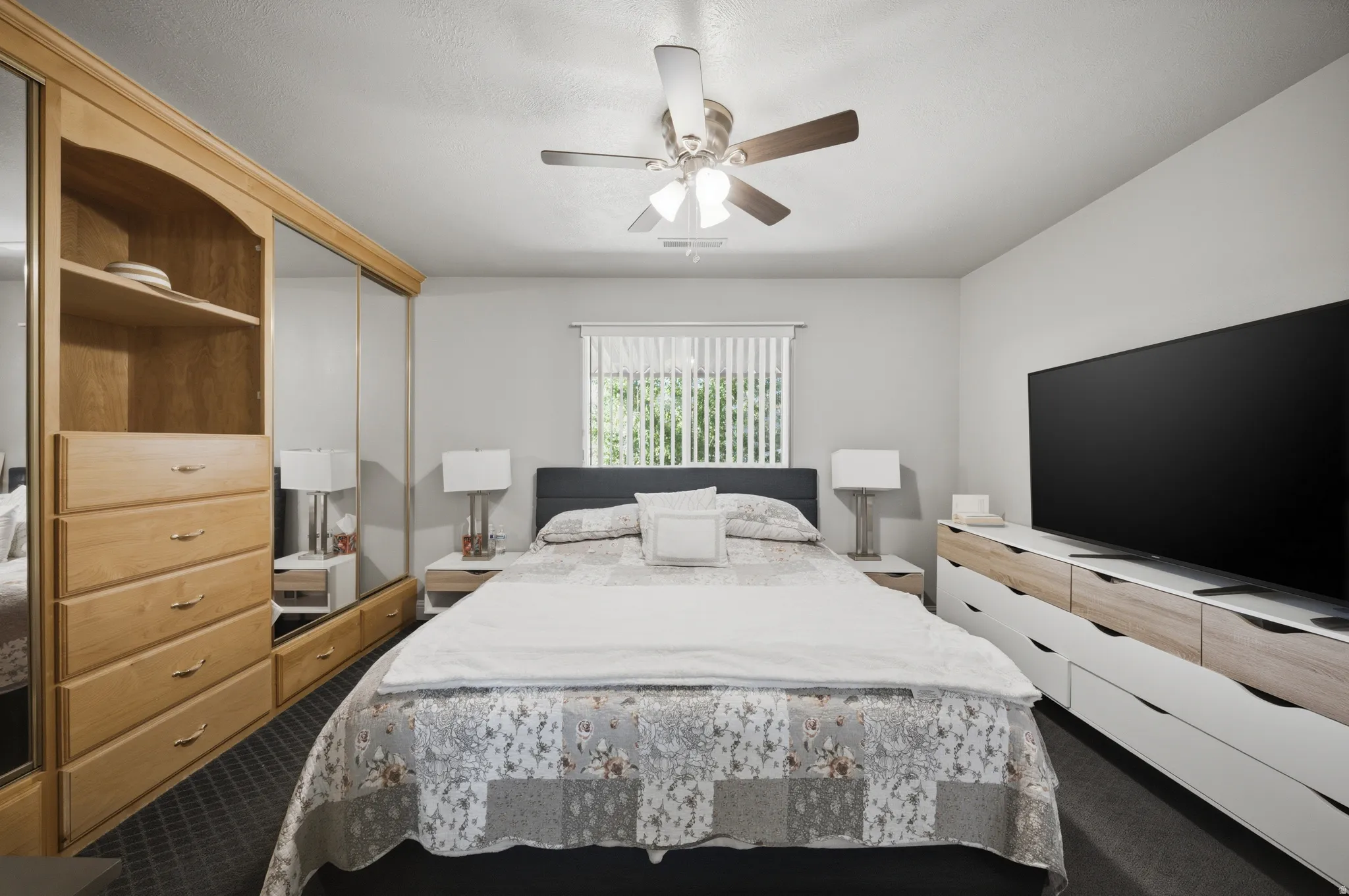 Bedroom with dark colored carpet, a ceiling fan, and a closet