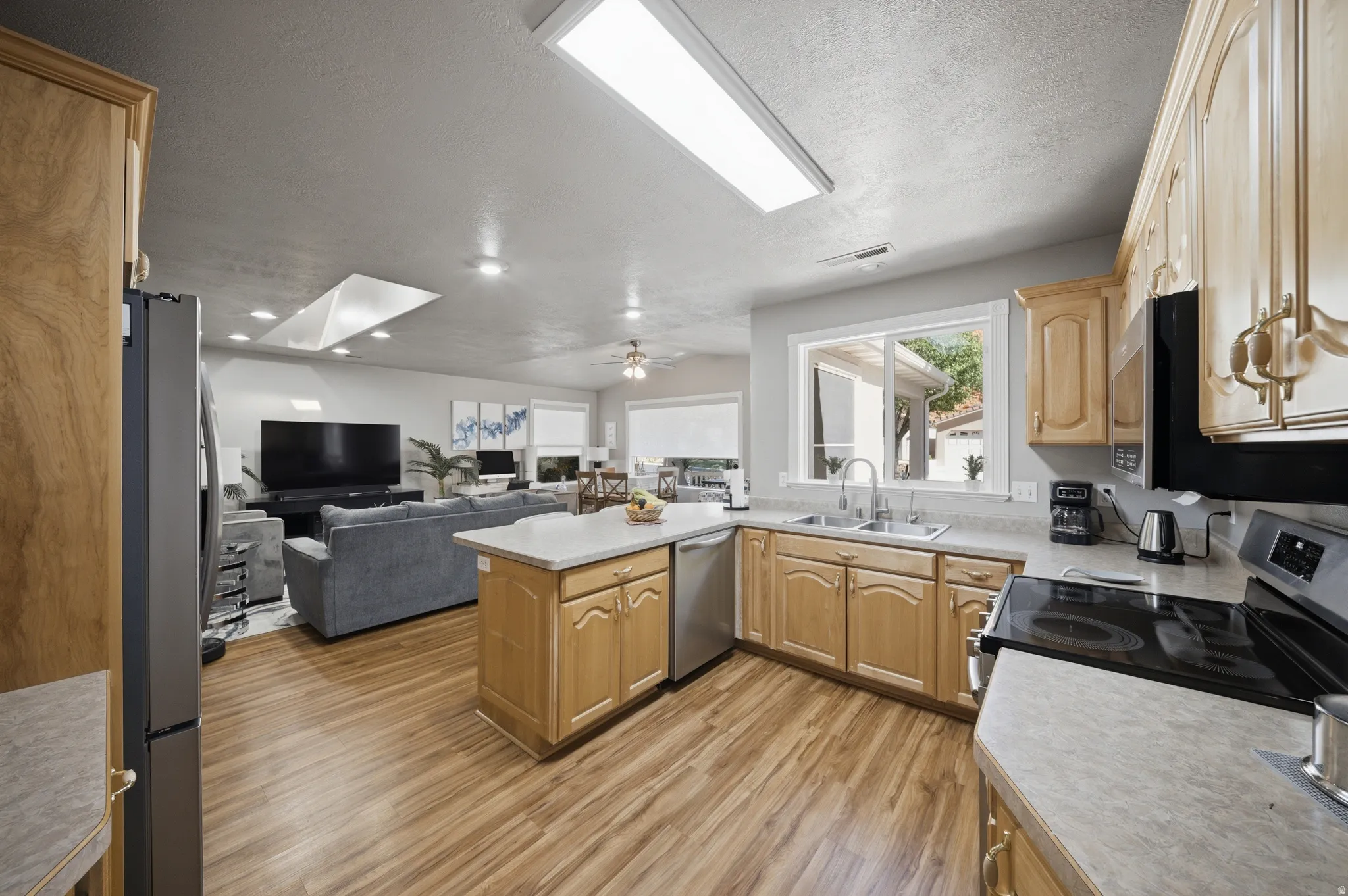 Kitchen with a peninsula, open floor plan, light countertops, stainless steel appliances, and light wood finished floors