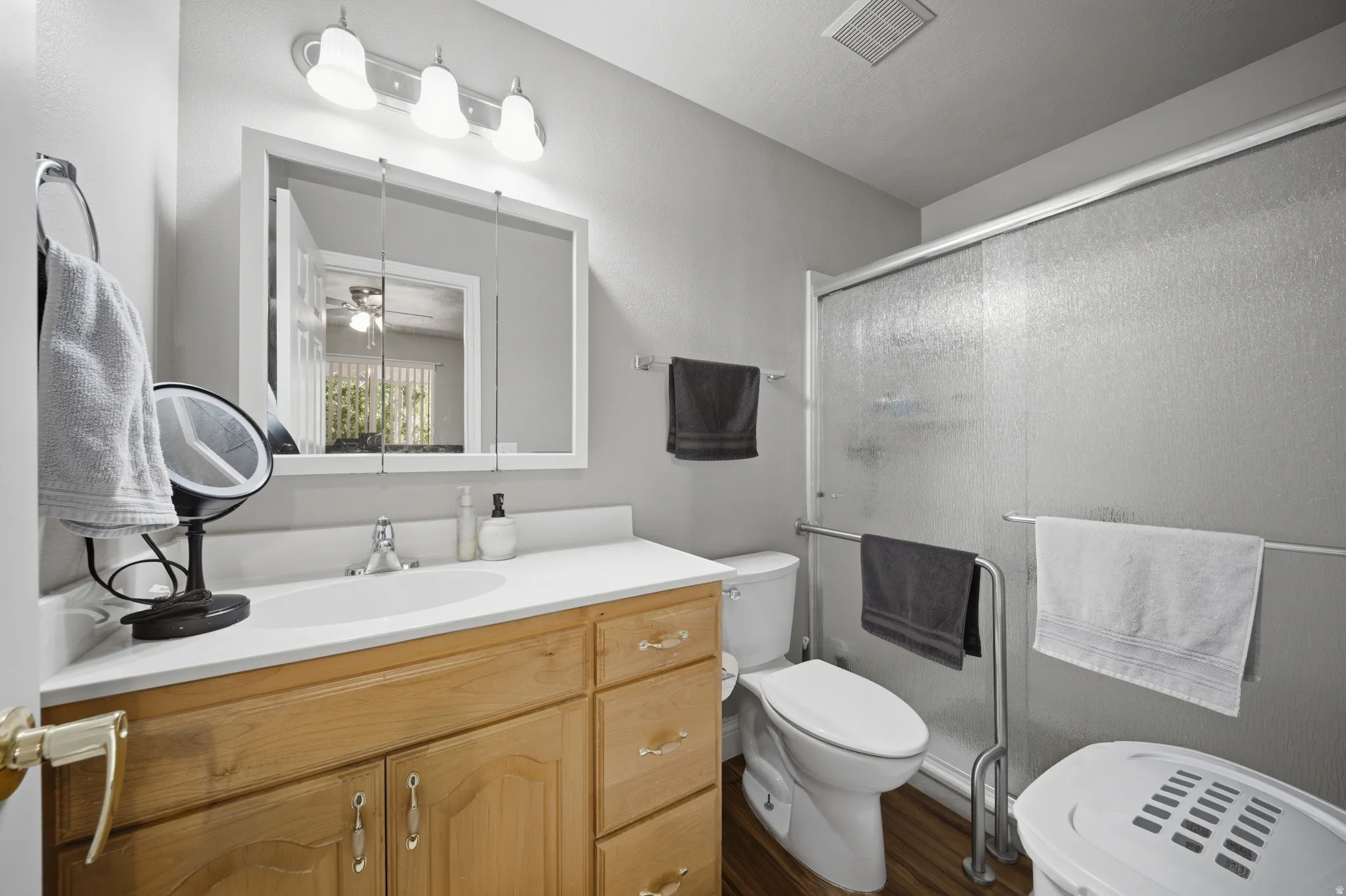 Full bathroom with vanity, a stall shower, ceiling fan, and dark wood-style flooring
