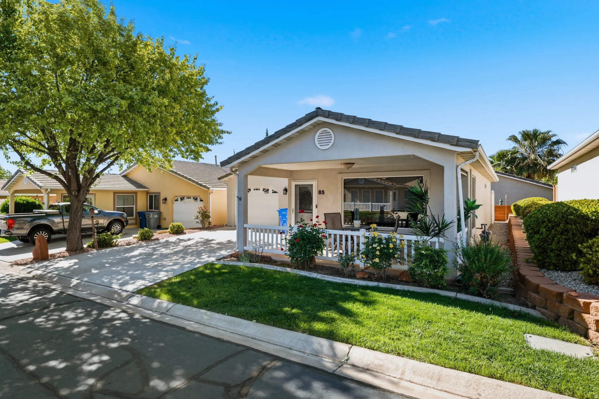 Ranch-style home with a porch, stucco siding, a front lawn, a garage, and concrete driveway
